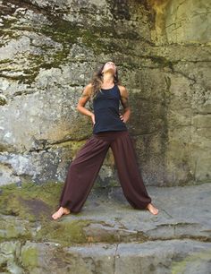 a woman in black shirt and brown pants standing on rocks