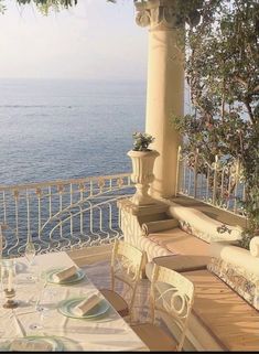 an outdoor dining area overlooking the ocean with table and chairs set up for two people