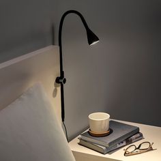 a lamp that is on top of a table next to some books and a cup