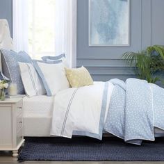 a bed with blue and white sheets, pillows and pillow cases on top of it