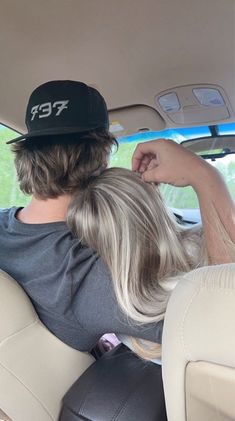 a man and woman sitting in the back seat of a car with their backs to each other