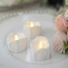 three white candles are sitting on a plate