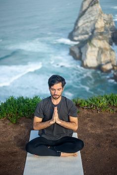 a man sitting in a yoga position with the ocean behind him