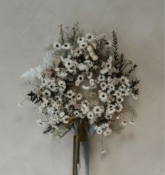 a bunch of flowers that are sitting on a white tablecloth and tied to a wall