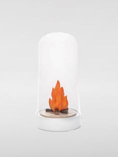 a small fire in a glass case on top of a white table with an orange flame