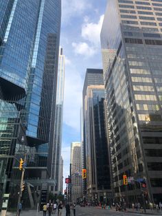 people are walking on the street in front of tall buildings with glass windows and skyscrapers