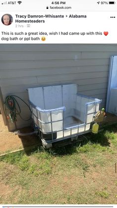 an empty trailer sitting in the grass next to a house with a hose attached to it