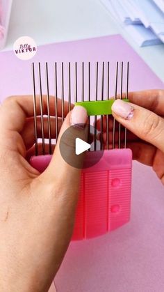 a person is holding a comb in front of a pile of pink and green material