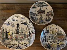 three plates with different designs on them sitting on a wooden table next to each other