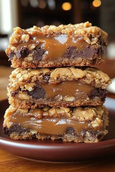 three pieces of chocolate peanut butter bars stacked on top of each other in a plate