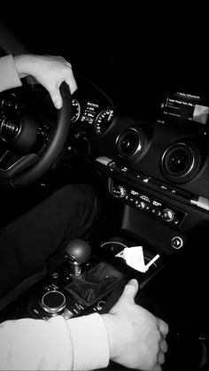 a person driving a car in the dark with their hands on the steering wheel and holding a remote control