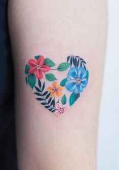 a heart shaped tattoo with flowers and leaves painted on the side of it's arm