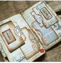 an open book with stamps on it sitting on top of a brown cloth covered table