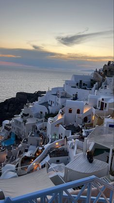 the sun is setting over some white buildings by the ocean in mykonos, greece