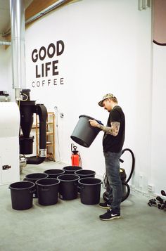 a man holding a bucket full of black cups