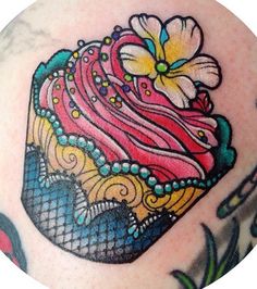 a colorful cupcake tattoo on the back of a woman's shoulder