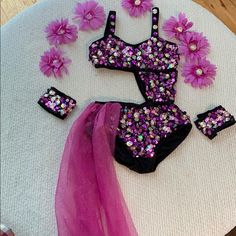 a pink and black swimsuit with purple flowers on it sitting on top of a table