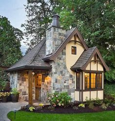 a small stone house in the middle of some grass