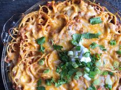 an enchilada dish with cheese, sour cream and cilantro garnish