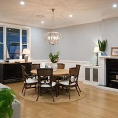 a dining room table and chairs in front of a fire place with a chandelier hanging from the ceiling