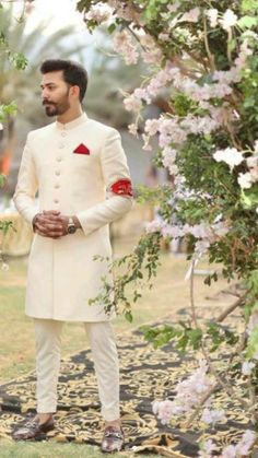 a man in a white suit standing under a tree