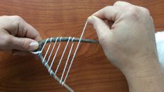 someone is making something out of wire on the wooden table and it looks like they are weaving