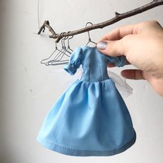 a hand holding a small blue bag hanging from a twig