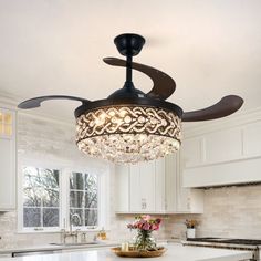 a ceiling fan in a kitchen with chandelier hanging from it's center