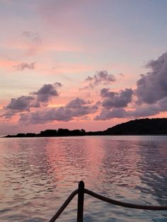 the sky is pink and purple as the sun sets over an island in the distance