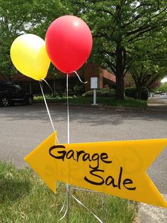 a yellow sign that says garage sale with red and yellow balloons