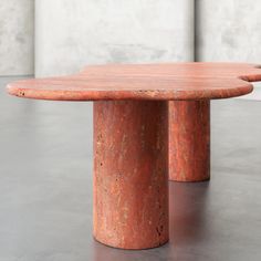 two red marble tables sitting next to each other on top of a cement flooring