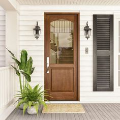 a house with a wooden front door and black shutters on the side walk, next to a large potted plant