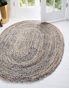 a round rug on the floor in front of a door with a potted plant next to it