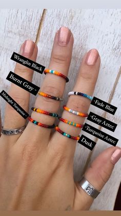 a woman's hand with five different rings on her fingers, all in different colors