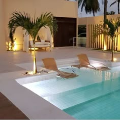 an indoor swimming pool with lounge chairs and palm trees