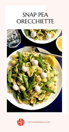 two white plates filled with pasta and asparagus on top of a blue table