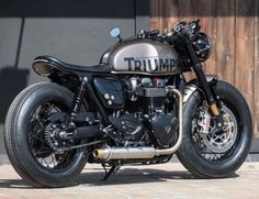 a triumph motorcycle parked in front of a wooden door with the words triumph on it