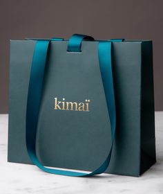 a blue bag with the name kimai on it sitting on a marble countertop