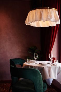 a table with two wine glasses on it in front of a red curtained window