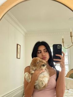 a woman taking a selfie in front of a mirror while holding a small bunny