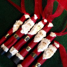 four red candles with santa clause faces on them, tied to a red ribbon and sitting on green grass