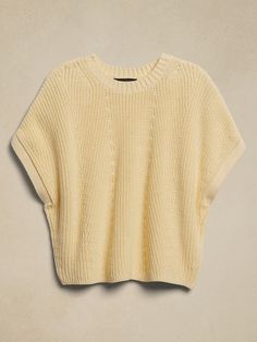 the cropped sweater is knitted in an off - white color, and has short sleeves