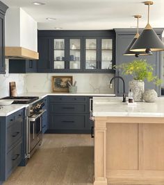 a large kitchen with blue cabinets and white counter tops, an island in the middle