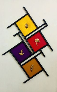 four different colored paintings on a white wall with black metal frames and gold accents in the middle