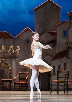 a young ballerina is dressed in white and posing for the camera