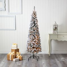 a white christmas tree with silver and gold ornaments next to two presents on a stand