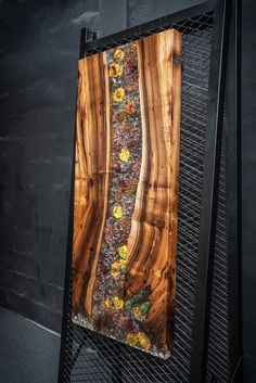 a piece of art made out of wood and metal with yellow flowers on the bottom