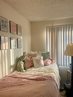 there is a bed with pillows and stuffed animals on it in the corner of this room