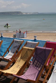 there are many beach chairs lined up on the sand near the water's edge