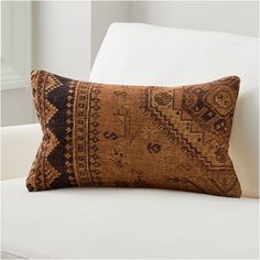 a brown and black pillow sitting on top of a white couch